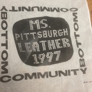 Souvenir handkerchief from MS PGH Leather 1997. White cloth. The words “COMMUNITY BOTTOM” form a square with “MS. PITTSBURGH LEATHER 1987” in white letter with a black border. 
